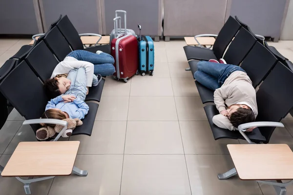 Family sleeping on airport seats in departure hall — Foto stock