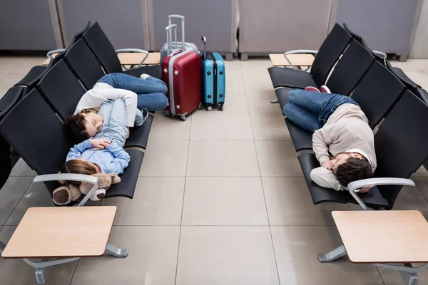 Family sleeping on airport seats in departure hall — Stockfoto