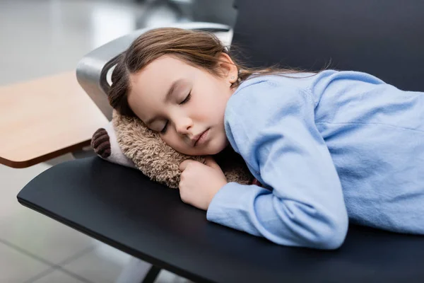 Kid sleeping on soft toy and airport seats in departure hall — Photo de stock