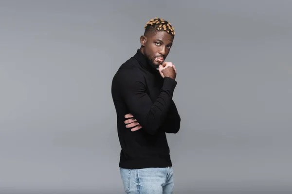 Stylish african american man with vitiligo holding hand near face while looking at camera isolated on grey — Photo de stock