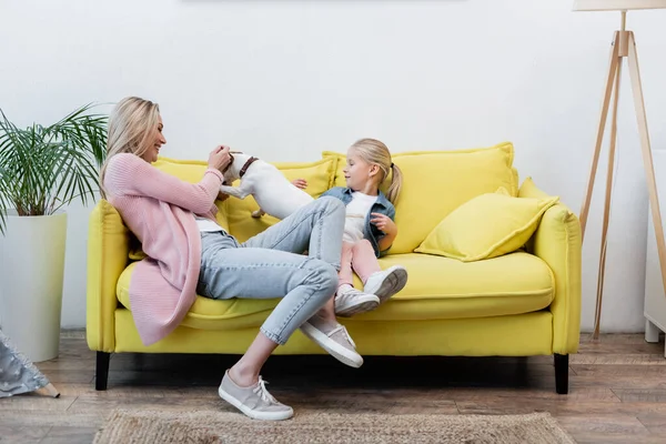 Щаслива сім'я грає з джек-тер'єром на дивані вдома — стокове фото