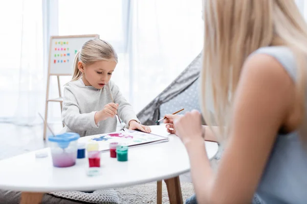 Kid drawing on sketchbook near mother at home — Fotografia de Stock