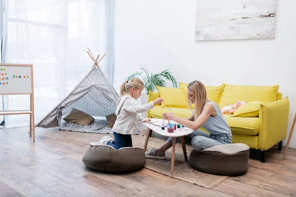 Happy mom and kid drawing on sketchbook near daughter at home — Fotografia de Stock