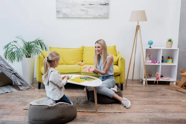 Smiling woman holding plasticine near child at home — Stock Photo