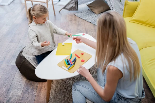 High angle view of mother giving plasticine to daughter at home — Stockfoto