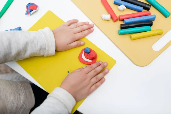 Cropped view of kid holding board near plasticine at home — Photo de stock