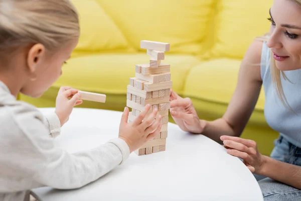 Blurred child playing wood blocks game with parent on coffee table at home — Fotografia de Stock