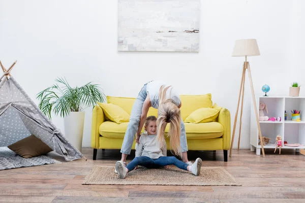 Woman touching smiling daughter while playing at home — стоковое фото