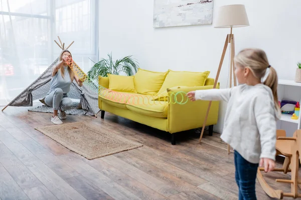 Blurred kid playing with slinky and mom at home — Stock Photo