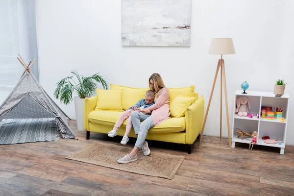 Parent hugging upset kid on couch at home — стоковое фото