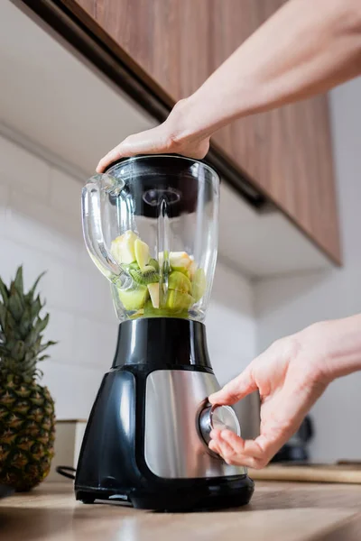 Ausgeschnittene Ansicht einer Frau, die Frucht-Smoothie im Mixer in der Küche zubereitet — Stockfoto