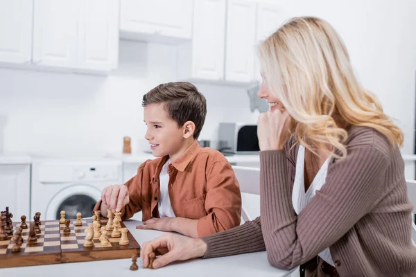 Positiver Junge spielt Schach bei Oma in Küche — Stockfoto