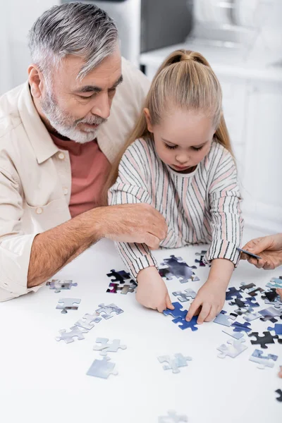 Senior homme jouant puzzle jeu avec petite-fille — Photo de stock