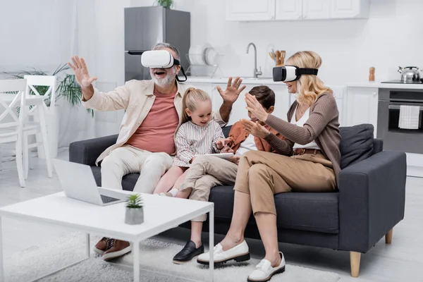 Children using digital tablet near excited grandparents gaming in vr headsets — Stock Photo