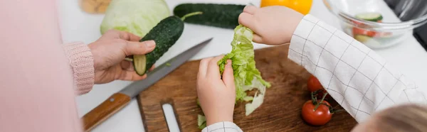 Vue du dessus de la femme cultivée et de l'enfant près des légumes frais sur la table de cuisine, bannière — Photo de stock