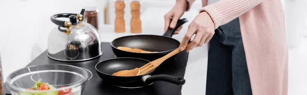 Partial view of housewife cooking pancakes on frying pans, banner — Stock Photo