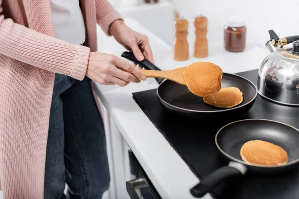 Cropped view of woman with spatula cooking pancakes on frying pans — Stock Photo