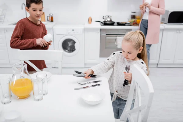 Kinder decken Tisch in Küche, während Oma Frühstück zubereitet — Stockfoto