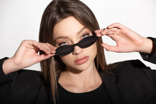 Portrait of pretty brunette woman looking at camera over black sunglasses isolated on grey — Stock Photo