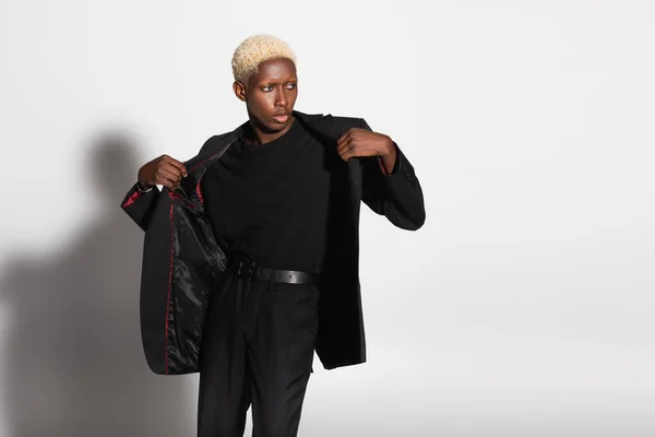 Homme afro-américain à la mode avec les cheveux blanchis se déshabiller sur gris avec ombre — Photo de stock