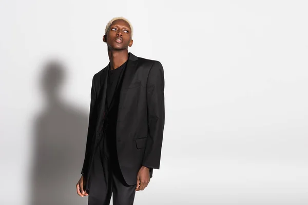 African american man with bleached hair looking away on grey with shadow — Stock Photo