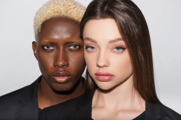 Blonde african american man and pretty brunette woman looking at camera isolated on grey — Stock Photo