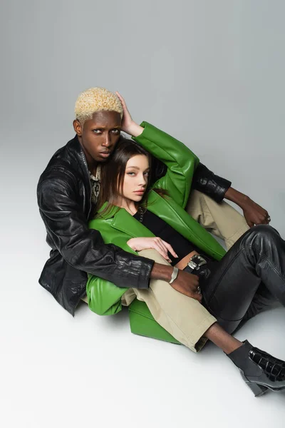 High angle view of brunette woman and blonde african american man hugging while sitting on grey — Stock Photo