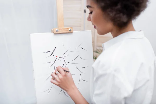 Side view of young african american woman painting on canvas at home — Stock Photo