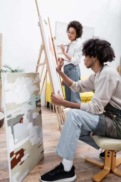 Couple afro-américain peinture sur chevalets dans le salon — Photo de stock