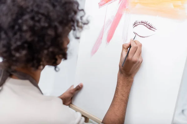 Blurred afroamericano hombre pintura sobre lienzo en casa - foto de stock