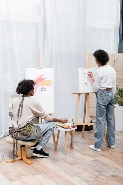 Joven pareja afroamericana pintando sobre lienzos en casa - foto de stock
