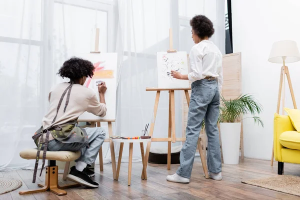 Couple afro-américain peinture sur toiles dans le salon — Photo de stock