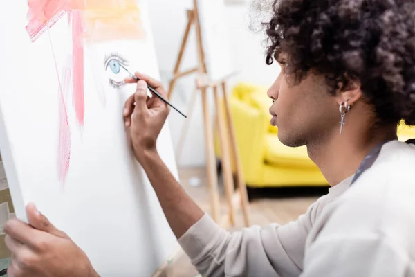 Side view of african american man painting on blurred canvas at home — Stock Photo