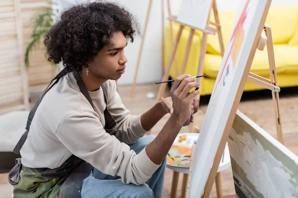 Jovem afro-americano pintando sobre tela em casa — Fotografia de Stock