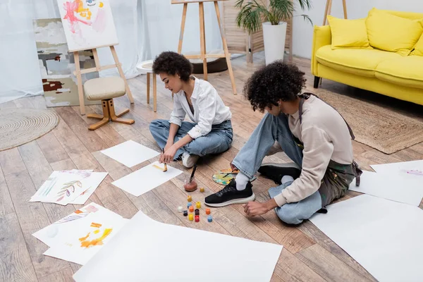 Young african american couple painting while sitting on floor at home — Stock Photo