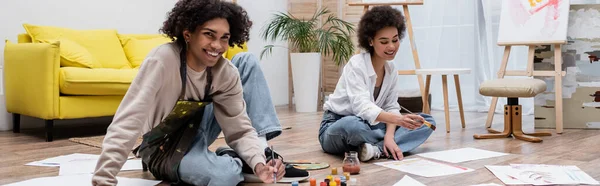 Smiling african american couple painting on floor near paints at home, banner — Stock Photo