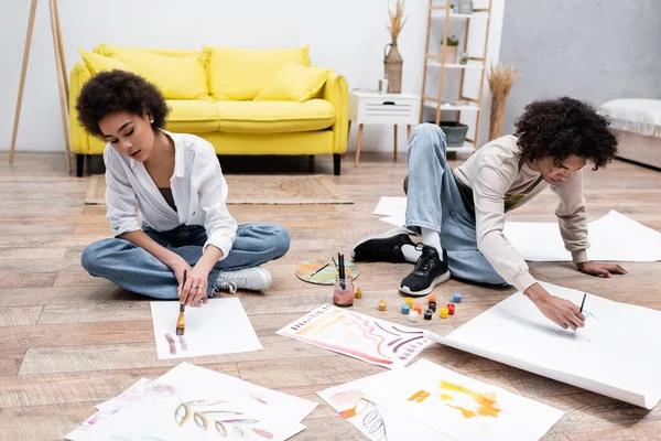 African american couple painting on papers on floor in living room — Stock Photo
