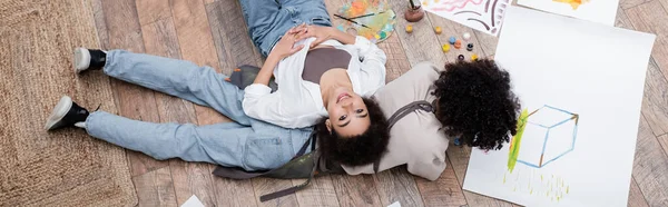 Top view of african american woman smiling near boyfriend painting on floor at home, banner — Stock Photo