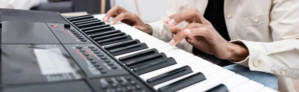 Cropped view of african american man playing synthesizer at home, banner — Stock Photo