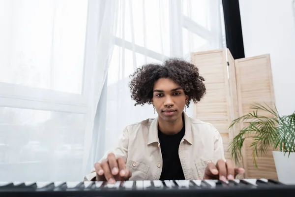 Young african american man playing blurred synthesizer at home — Stock Photo