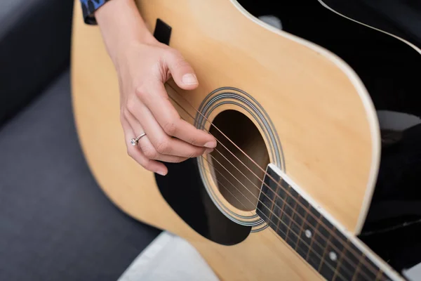 Vista ritagliata della donna afro-americana che suona la chitarra acustica sul divano — Foto stock