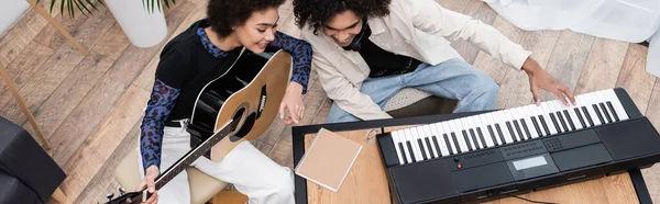 Vista aerea della giovane coppia afroamericana che suona strumenti musicali a casa, striscione — Foto stock