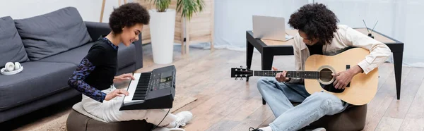 Sorrindo casal afro-americano tocando instrumentos musicais perto de fones de ouvido e laptop em casa, banner — Fotografia de Stock