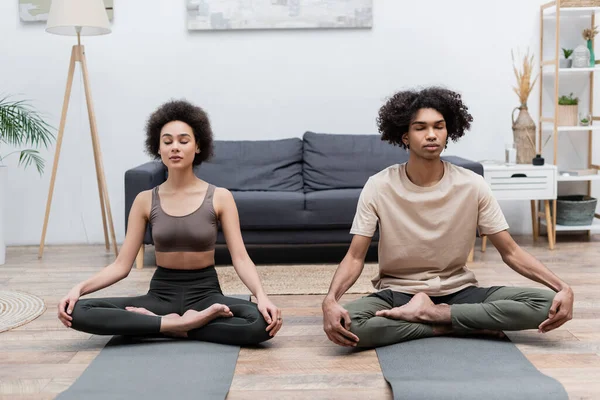 Junges afrikanisch-amerikanisches Paar meditiert zu Hause auf Yogamatten — Stockfoto