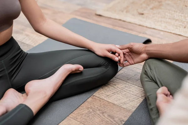 Cropped view of african american man holding hand of girlfriend while meditating at home — Stock Photo