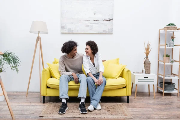 Усміхаючись афроамериканською парою сидячи на дивані у вітальні. — стокове фото