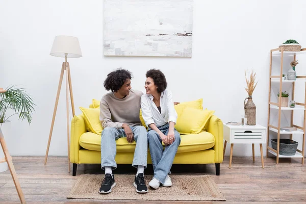 Souriant couple afro-américain assis sur le canapé dans le salon — Photo de stock