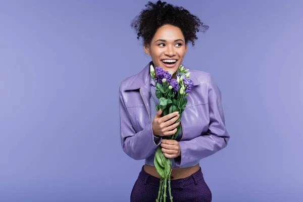 Allegra giovane donna afroamericana in possesso di bouquet di fiori isolati su viola — Foto stock