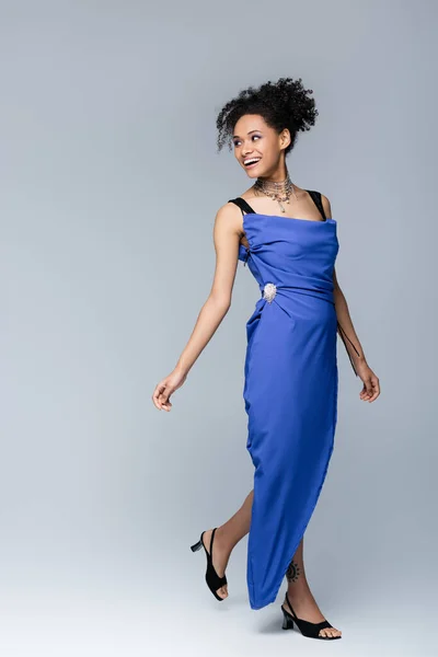 Full length of happy african american woman in bright blue dress on grey — Stock Photo