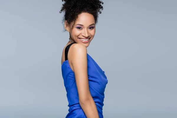 Happy african american woman in bright slip dress looking at camera while posing isolated on grey — Stock Photo